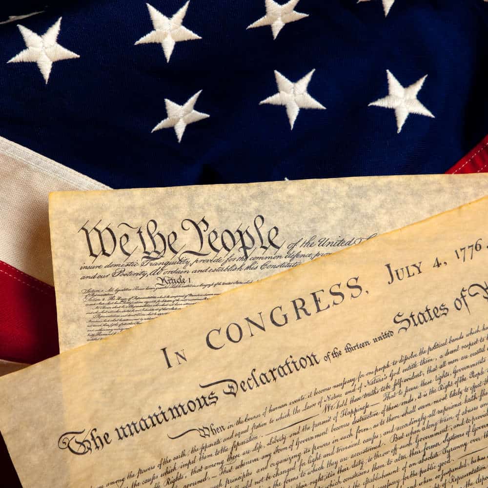 United States' Constitution and Declaration of Independence on a flag background