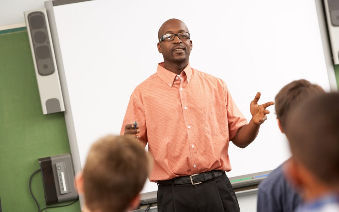 Teacher Talking To Class Standing In Front Of Whiteboard