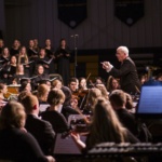 director leading orchestra and choir