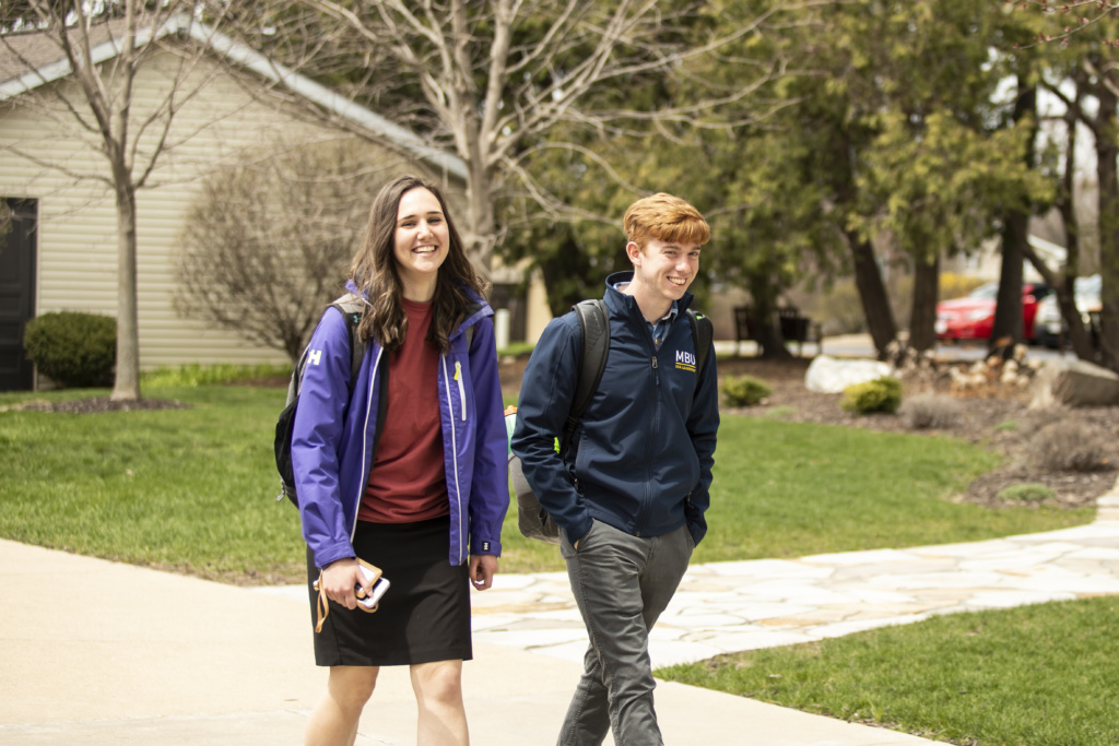 Two students enjoying a walk across campus, like you could on a campus visit.